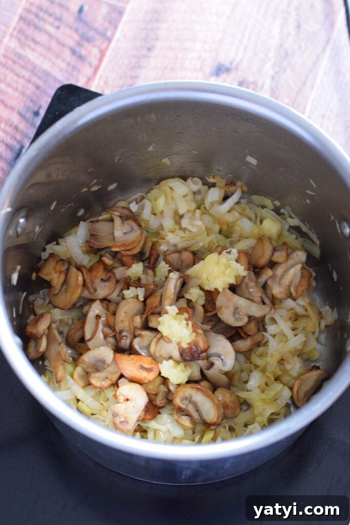 Creamy Mushroom and Leek Risotto Recipe for Cozy Dinners 9 cooking mushrooms and leeks in a saucepan.