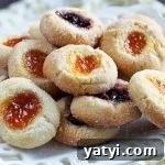 Jam-filled thumbprint cookies on a square white serving dish.
