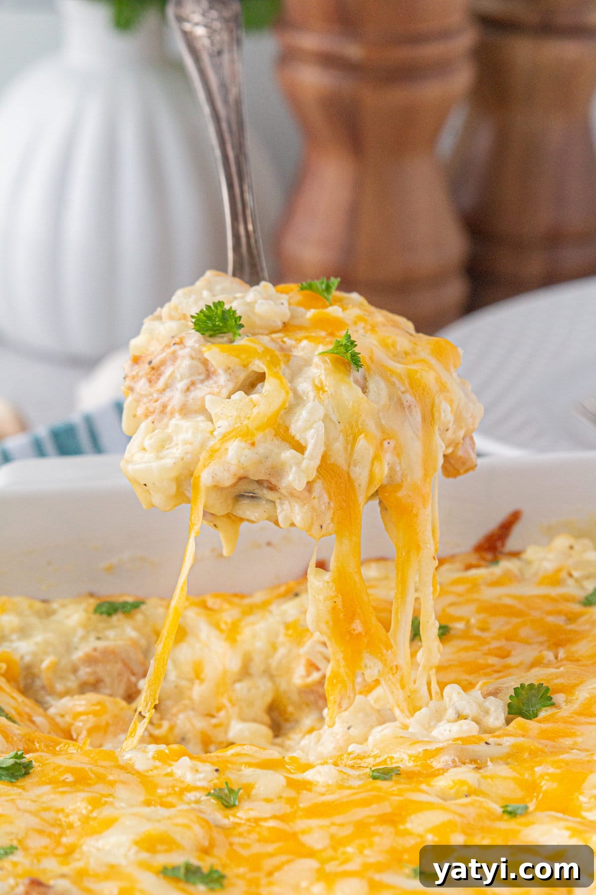 Creamy Angel Chicken and Rice Casserole Recipe 2 A scoop of angel chicken and rice with strings of cheese hovered over the casserole dish.
