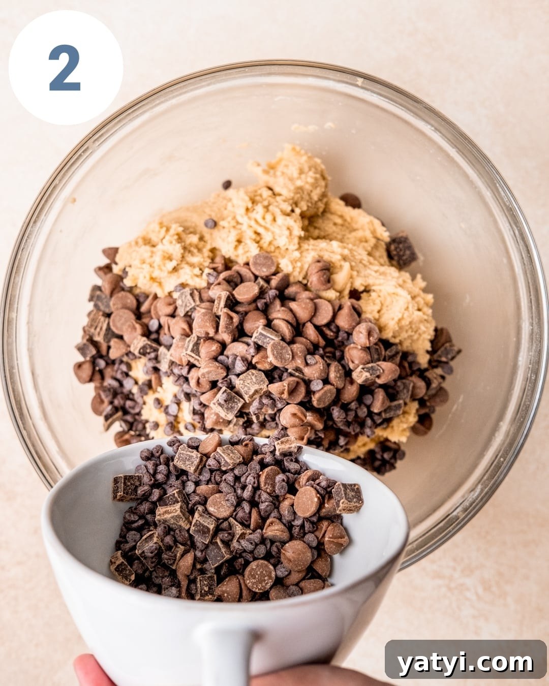 Ultimate Chewy Chocolate Chip Cookie Recipe 5 Pouring chocolate chips into cookie dough.