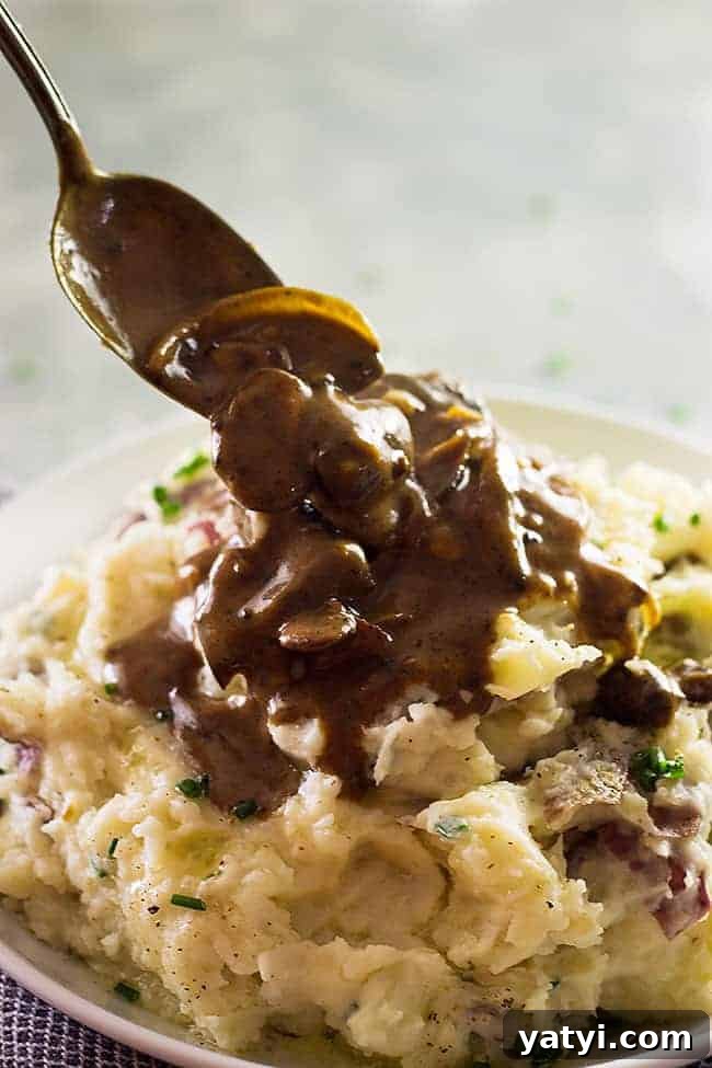 Creamy Chunky Mashed Potatoes with Rustic Texture 4 closeup: pouring a mushroom gravy over my chunky mashed potatoes recipe