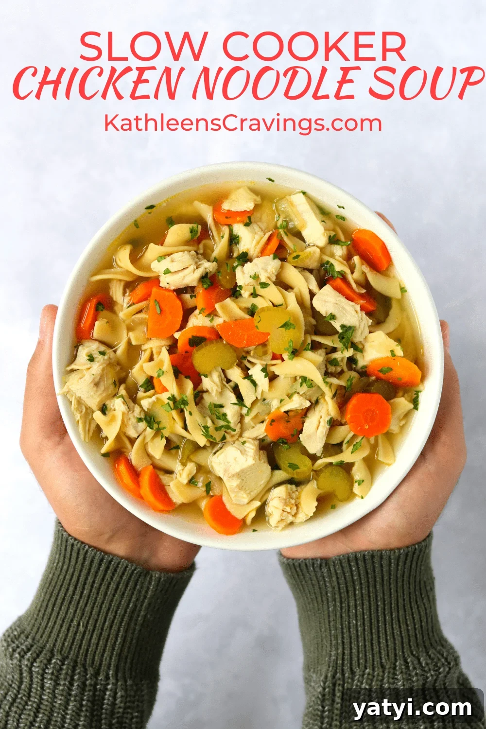Hearty Slow Cooker Chicken Noodle Soup Recipe 2 Hands holding bowl of chicken noodle soup made in the slow cooker.